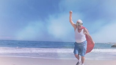 Plajda süper kahraman kostümü giyen yaşlı, beyaz bir adamın üzerindeki bulutların animasyonu. eğlence ve eğlence konsepti dijital olarak oluşturulmuş video.