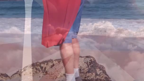 灰色的云彩笼罩着在海滩上穿着超级英雄服装的资深高加索人 康乐及娱乐概念数码影片 — 图库视频影像