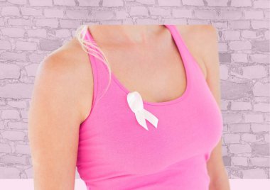 Arka plandaki tuğla duvara karşı koluna pembe kurdele takan bir kadın. Göğüs kanseri farkındalığı kavramı