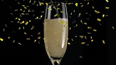 Şampanya kadehinin üzerine siyah arka planda düşen altın konfetilerinin animasyonu. Yılbaşı partisi kutlaması konsepti dijital olarak oluşturulmuş video.