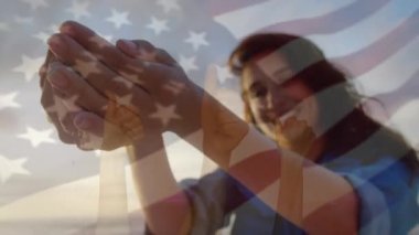 Sahilde eğlenen bir kadının üzerinde ABD bayrağı sallaması. seyahat, tatiller, vatanseverlik ve dijital olarak üretilen video konsepti.