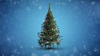 Yılbaşı ağacının üzerine düşen kar mavi arka planda kar tanelerine çarpıyor. Noel şenliği ve kutlama konsepti