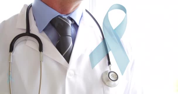 白地に笑顔の白人男性医師の上に青い癌リボンのアニメーション がんの肯定的な認知キャンペーン医療サービスコンセプトデジタルで生成されたビデオ — ストック動画