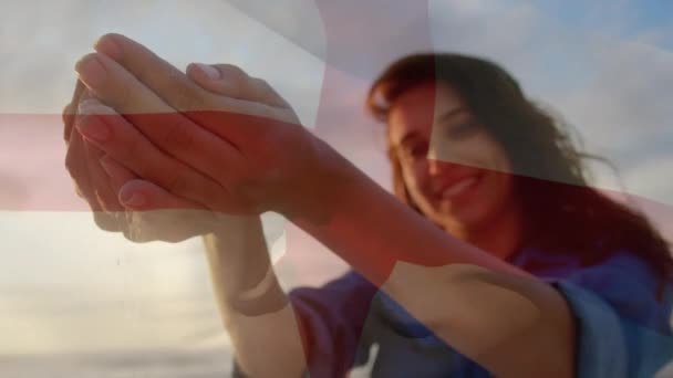 ビーチで楽しんでいる女性の上に英国の旗を振ってアニメーション 愛国心とお祝いの概念デジタルで生成されたビデオ — ストック動画