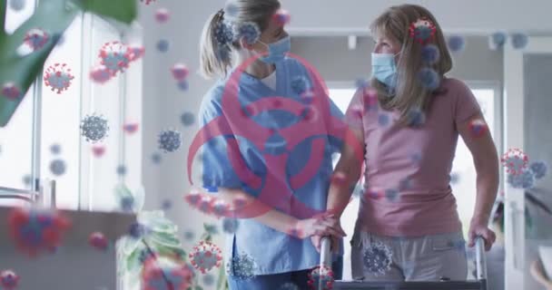 与戴口罩的高加索老年妇女和护士相比 病毒细胞和生物危害图标的动画化 全球联盟19大流行病概念数码视频 — 图库视频影像