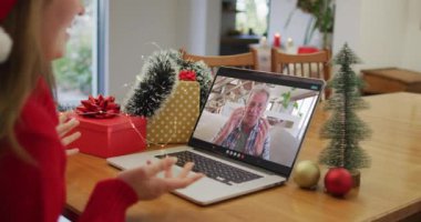 Noel 'de büyükbabamla görüntülü görüşme yapan mutlu beyaz kadın. Noel, şenlik ve iletişim teknolojisi.