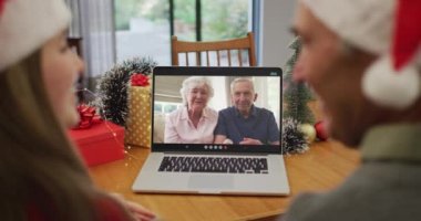 Kafkasyalı torun ve büyükbaba noel zamanı yaşlı bir çiftle görüntülü görüşmede. Noel, şenlik ve iletişim teknolojisi.