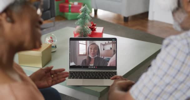 クリスマスの時に女性の友人とラップトップでビデオ通話で幸せなアフリカ系アメリカ人のカップル クリスマスやお祭りや通信技術は — ストック動画