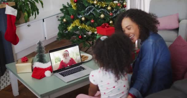 快乐的非洲裔美国人的母亲和女儿在圣诞节的时候与桑塔 克劳斯通过视频通话 圣诞节 节日和通信技术 — 图库视频影像