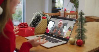 Noel 'de büyükbabamla görüntülü görüşme yapan mutlu beyaz kadın. Noel, şenlik ve iletişim teknolojisi.