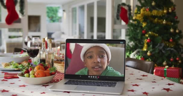 Happy african american boy in santa hat on laptop lying on christmas table. christmas, festivity and communication technology. — Stock Footage Happy African American Boy Santa Hat Laptop Lying Christmas Table Stock Video
