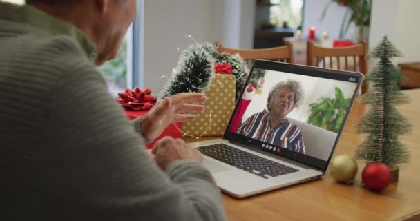 アフリカ系アメリカ人のシニア女性とクリスマスのビデオ通話をラップトップで持っている白人のシニア男性 クリスマスやお祭りや通信技術は — ストック動画