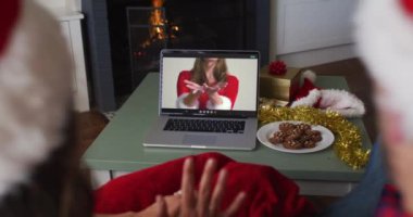 Laptop 'taki beyaz çift Noel zamanı bayan arkadaşıyla görüntülü görüşme yapıyor. Noel, şenlik ve iletişim teknolojisi.