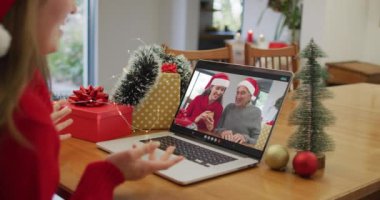 Noel 'de büyükanne ve büyükbabasıyla görüntülü görüşme yapan mutlu beyaz kadın. Noel, şenlik ve iletişim teknolojisi.