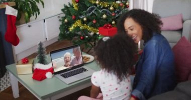 Mutlu Afro-Amerikan anne ve kızı dizüstü bilgisayardaki son sınıf öğrencisiyle Noel 'de görüntülü konuşma yapıyor. Noel, şenlik ve iletişim teknolojisi.