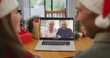 Kafkasyalı büyükbaba ve torun, yılbaşında son sınıf arkadaşlarıyla dizüstü bilgisayardan video görüşmesi yapıyor. Noel, şenlik ve iletişim teknolojisi.