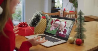 Noel 'de büyükanne ve büyükbabasıyla görüntülü görüşme yapan mutlu beyaz kadın. Noel, şenlik ve iletişim teknolojisi.