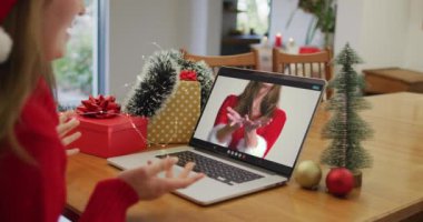 Yılbaşı zamanı laptopta bayan arkadaşıyla görüntülü konuşan beyaz bir kadın. Noel, şenlik ve iletişim teknolojisi.