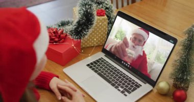 Noel zamanı dizüstü bilgisayarında Noel Baba 'yla görüntülü beyaz kadın. Noel, şenlik ve iletişim teknolojisi.