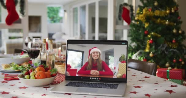 坐在笔记本电脑上戴着圣诞礼帽的快乐的高加索女人躺在圣诞桌上 圣诞节 节日和通信技术 — 图库视频影像