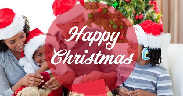 サンタの帽子をかぶって笑顔アフリカ系アメリカ人の家族の上に幸せなクリスマステキストの構成 クリスマス冬伝統お祝いのコンセプトデジタルで生成されたイメージ — ストック写真