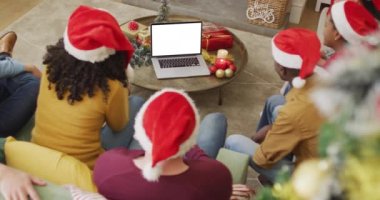 Noel Baba şapkalı çeşitli gülümseyen arkadaşlar dizüstü bilgisayarda noel için video çağrısı yapıyorlar ve ekranda da kopya alanı var. Noel, şenlik ve iletişim teknolojisi.