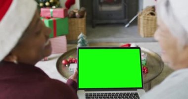 Noel Baba şapkalı, yeşil ekranlı, dizüstü bilgisayarlı, kıdemli, değişik tipte bir çift. Noel, şenlik ve iletişim teknolojisi.