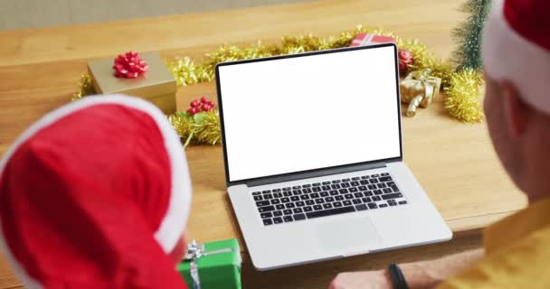 サンタの帽子の息子と白人の父親は ラップトップのクリスマスビデオ通話を行い 画面上のスペースをコピーします クリスマスやお祭りや通信技術は — ストック動画