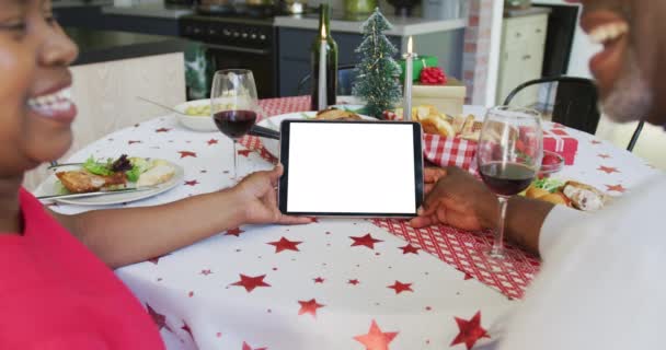 アフリカ系アメリカ人のカップルがタブレットクリスマスビデオ通話をしたり 画面上のスペースをコピーしたりします クリスマスやお祭りや通信技術は — ストック動画
