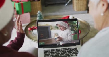 Üst düzey bayan arkadaşlar, ekranda beyaz bir çocukla yılbaşı görüntüsü için dizüstü bilgisayar kullanıyorlar. Noel, şenlik ve iletişim teknolojisi.