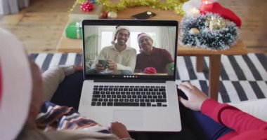 Afrika kökenli Amerikalı anne ve kız, ekranda ailesiyle birlikte yılbaşı görüntülü konuşma için dizüstü bilgisayar kullanıyorlar. Noel, şenlik ve iletişim teknolojisi.