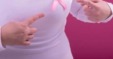 Beyaz kadın, pembe arka planda pembe kanser farkındalığı kurdelesi takıyor. Göğüs kanseri pozitif farkındalık kampanyası konsepti.