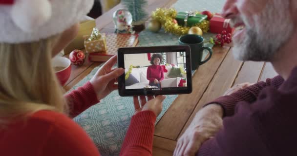 画面上の笑顔の友人とクリスマスのビデオ通話のためのタブレットを使用してサンタの帽子と白人のカップル クリスマスやお祭りや通信技術は — ストック動画