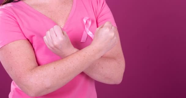 ピンクの癌意識リボンをつけて腕を交差させた白人女性の真ん中の動画 乳がん認知キャンペーンのコンセプト — ストック動画
