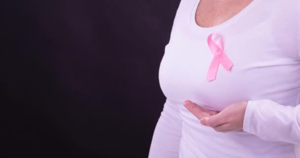身着粉色癌症认知带 背景为黑色的高加索女性中段视频 乳腺癌积极认识运动概念 — 图库视频影像