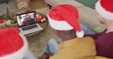 Noel Baba şapkalı çeşitli aileler, ekranlarında çift olan bir çiftin Noel görüntülü araması için laptop kullanıyorlar. Noel, şenlik ve iletişim teknolojisi.