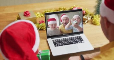 Oğlu beyaz bir baba, Noel 'de dizüstü bilgisayar kullanıyor. Ailesi de ekranda. Noel, şenlik ve iletişim teknolojisi.