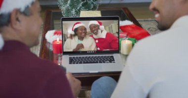 Gülümseyen çift ırklı baba ve oğul, dizüstü bilgisayarını ekranda çift olarak Noel 'de görüntülü konuşma yapmak için kullanıyor. Noel, şenlik ve iletişim teknolojisi.
