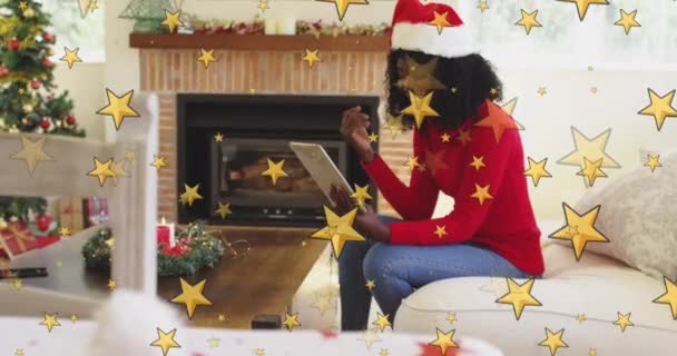 Желтые Звёзды Против Африканской Американки Играющей Цифровом Планшете Время Рождества — стоковое видео