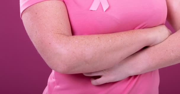 身着粉色癌症认知带 背景为粉色的高加索女性的中间段视频 乳腺癌积极认识运动概念 — 图库视频影像