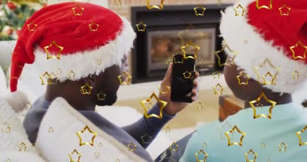 圣诞期间 金色的明星形象与父亲和儿子在智能手机上玩视频的情景相遇 圣诞节的庆祝和庆祝概念 — 图库视频影像