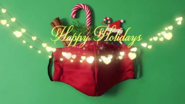 緑の背景にライトやフェイスマスク上の幸せな休日のクリスマステキストのアニメーション Covid 19パンデミックのクリスマス お祝いのコンセプトデジタルで生成されたビデオ — ストック動画