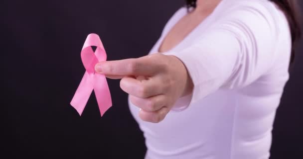 视频中的高加索女人拿着粉红的癌症意识带 黑色背景 乳腺癌积极认识运动概念 — 图库视频影像