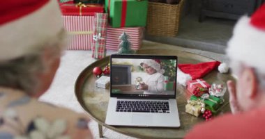 Üst düzey Kafkasyalı çift, ekranda gülümseyen çocukla yılbaşı videosu için dizüstü bilgisayar kullanıyor. Noel, şenlik ve iletişim teknolojisi.