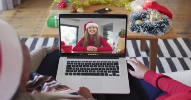 Afrika kökenli Amerikalı anne ve kız. Ekrandaki kadınla yılbaşı videosu için dizüstü bilgisayar kullanıyorlar. Noel, şenlik ve iletişim teknolojisi.