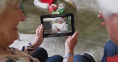 Üst düzey Kafkasyalı çift, ekranda gülümseyen çocukla Noel videosu için tablet kullanıyor. Noel, şenlik ve iletişim teknolojisi.