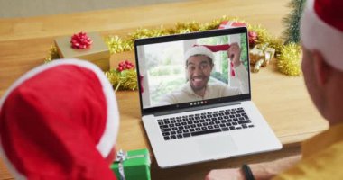 Noel Baba 'nın beyaz babası ve Noel Baba şapkalı, dizüstü bilgisayarını ekranda bir adamla yılbaşı görüntüsü için kullanıyor. Noel, şenlik ve iletişim teknolojisi.