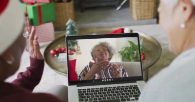 İki farklı son sınıf kız arkadaşı, ekranda kadınla birlikte yılbaşı videosu için dizüstü bilgisayar kullanıyor. Noel, şenlik ve iletişim teknolojisi.