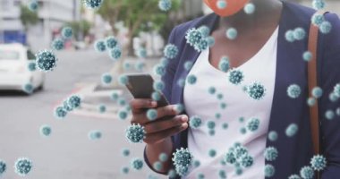 Afro-Amerikan kadınının akıllı telefon kullanarak yüz maskesi taktığı Coperid 19 hücrenin animasyonu. küresel covid 19 salgın konsepti dijital olarak oluşturulmuş video.