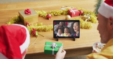 Beyaz bir baba ve oğlu Noel 'de ekranda gülümseyen bir aileyle birlikte tablet kullanıyor. Noel, şenlik ve iletişim teknolojisi.